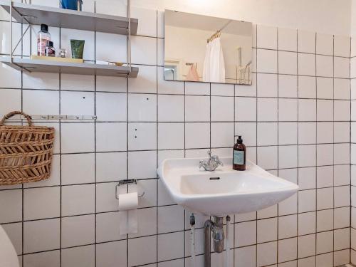 Baño de azulejos blancos con lavabo y espejo en Holiday home Bedsted Thy IV, en Bedsted Thy