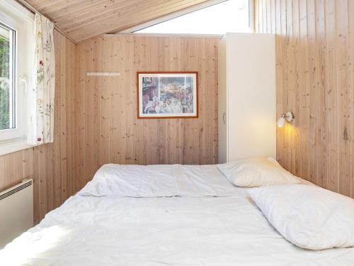 a bed in a room with wooden walls and a window at 14 person holiday home in Væggerløse-By Traum in Marielyst