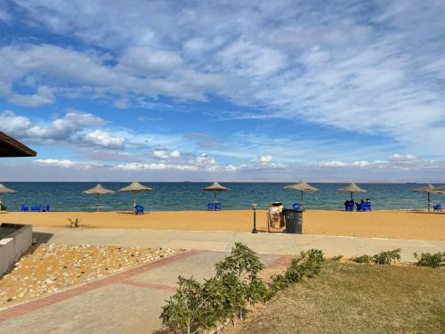 una playa con sombrillas y sillas y el océano en شاليه بقرية كورونادو مارينا - Coronado Marina عائلات فقط, en Ain Sokhna