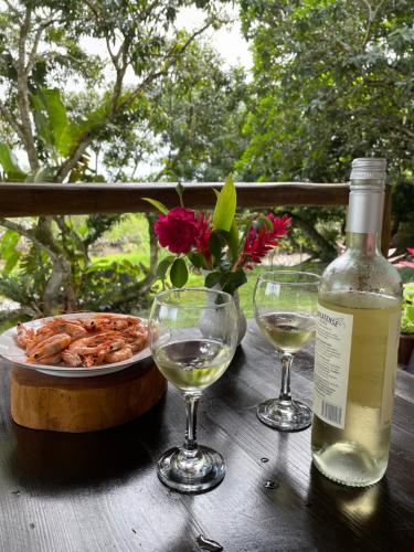 uma garrafa de vinho e dois copos numa mesa de madeira em Vila Marés em São Cristóvão