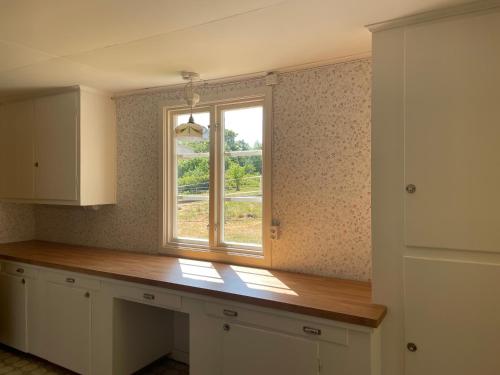a kitchen with a window and a wooden counter at Cottage with beautiful nature, open landscape, forest and lakes in Tingsryd