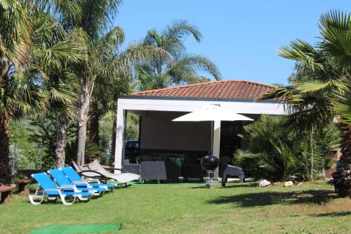 un grupo de sillas y un paraguas en un patio en Villa Assia, en Gaeta