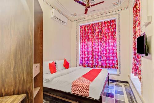 Schlafzimmer mit einem Bett und einem Fenster mit roten Vorhängen in der Unterkunft OYO Flagship 77120 Hotel Achrol Haveli Sukher in Udaipur