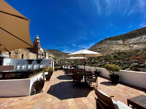 eine Terrasse mit Tischen, Stühlen und einem Sonnenschirm in der Unterkunft HOTEL MINA REAL in Real de Catorce