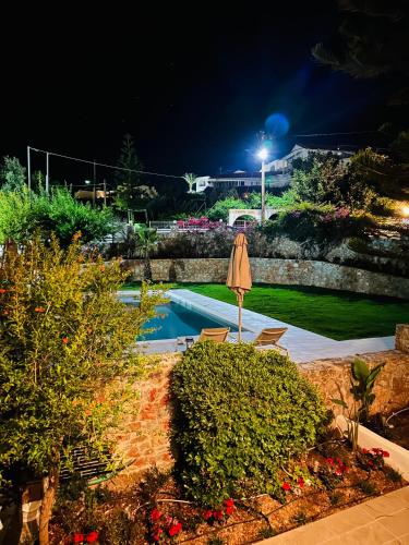 a swimming pool at night with an umbrella and bushes at Cost Mari Almyrida New by ZAGO Boutiqe hotels in Almirida