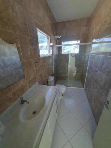 a bathroom with a sink and a shower and a toilet at Casarão de frente para a lagoa de Praia Seca in Praia Sêca