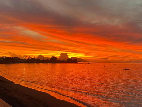 a sunset on the beach with a boat in the water at Royal Tahitien in Papeete