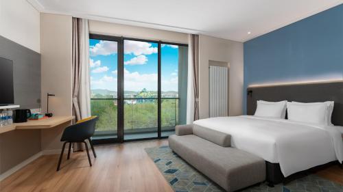 1 dormitorio con cama y ventana grande en Holiday Inn Express Dalian Golden Pebble Beach, an IHG Hotel en Dalian