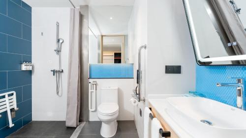 W łazience znajduje się umywalka, toaleta i lustro. w obiekcie Holiday Inn Express Dalian Golden Pebble Beach, an IHG Hotel w mieście Dalian