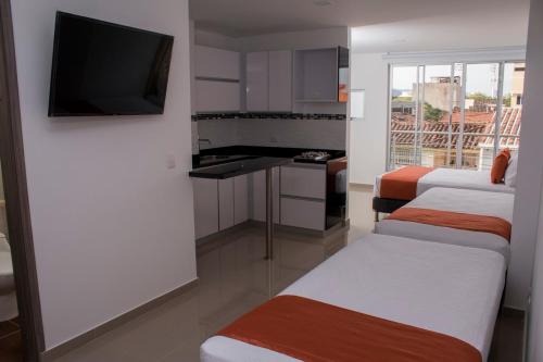 a room with three beds and a flat screen tv at ALESOMAYA APARTHOTEL in Cali