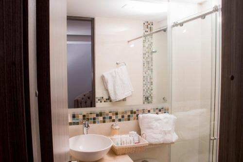 a white bathroom with a sink and a shower at ALESOMAYA APARTHOTEL in Cali