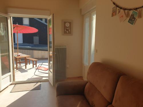 - un salon avec un canapé et une table avec un parasol dans l'établissement Notre nid - Grande terrasse privée en bord de mer, au coeur du quartier historique du Tréport ! Wifi, au Tréport