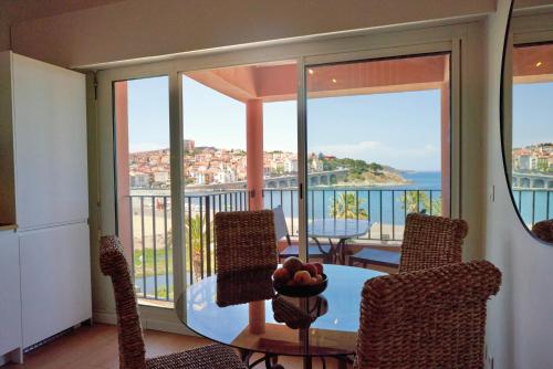 a balcony with a table and chairs with a view of the ocean at Vue Mer Panoramique Exceptionnelle l T2 Mezzanine Luxueux in Banyuls-sur-Mer