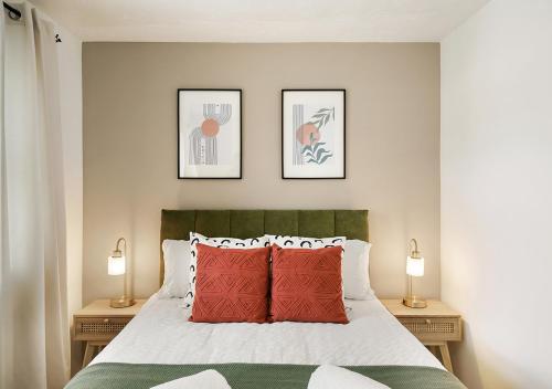 1 dormitorio con 1 cama con almohadas rojas y 2 lámparas en East London House near tube with parking, en Londres