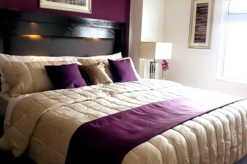 a bedroom with a large bed with purple pillows at Torre Pamplona 409 -Nuevo y Cómodo- Apartamento in Guatemala