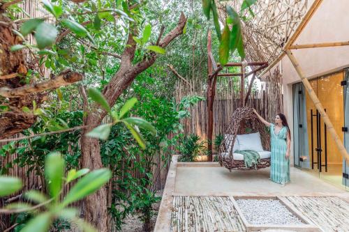 a woman standing on a porch with a swing at Hotel Villas Flamingos in Holbox Island
