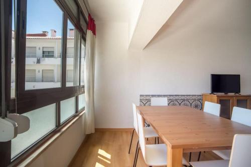 a dining room with a wooden table and a window at Sunny Marisol T2 in Aroeira