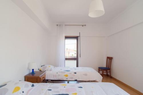 a bedroom with two beds and a table and a chair at Sunny Marisol T2 in Aroeira