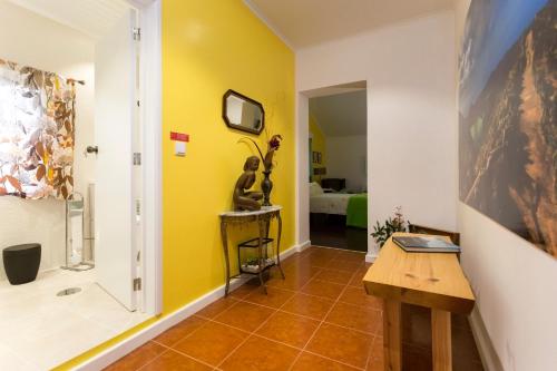 a hallway with a yellow wall and a tv on a wall at Casa do Calço in Ponta Delgada