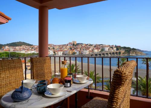 a table on a balcony with a view of the beach at Vue Mer Panoramique Exceptionnelle l T2 Mezzanine Luxueux in Banyuls-sur-Mer