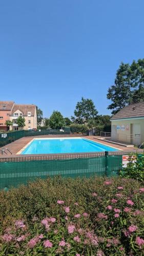 - une grande piscine dans une cour ornée de fleurs roses dans l'établissement Appartement T3 - Relax aux portes des 24h du Mans, au Mans