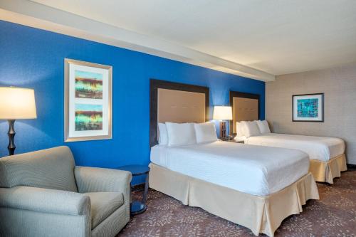 a hotel room with two beds and a chair at Holiday Inn - Terre Haute, an IHG Hotel in Terre Haute