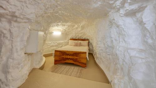 um pequeno quarto com uma cama numa parede de pedra falsa em Desert Hideaway - Underground living - White Cliffs em White Cliffs
