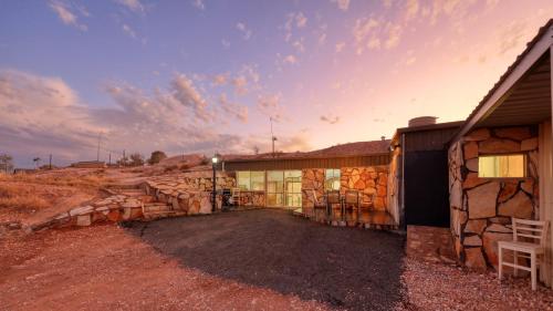 a building with a pile of logs in front of it at Desert Hideaway - White Cliffs in White Cliffs