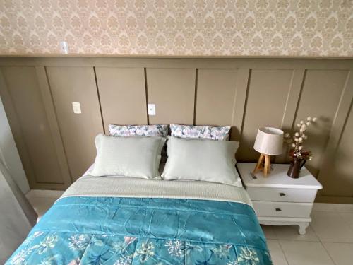 a bed with blue and white sheets and pillows at Hotel APART Zuccolotto 301 in Aracruz