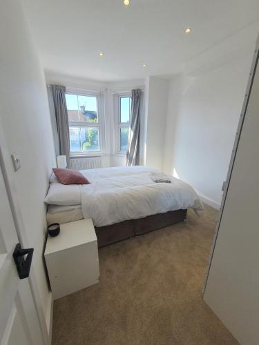 a white bedroom with a bed and a window at Blue house in Edgware