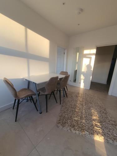 une salle à manger avec une table, des chaises et un tapis dans l'établissement Blue house, à Edgware