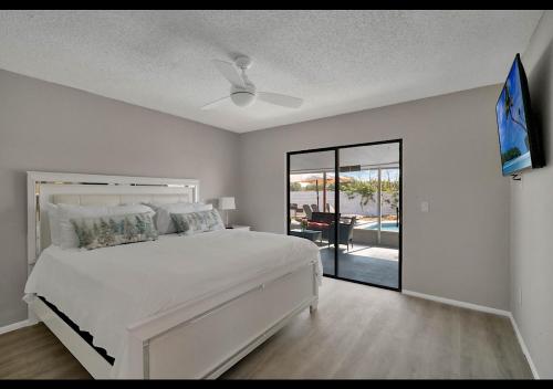 a white bedroom with a bed and a sliding glass door at The Cozy spot in Orlando