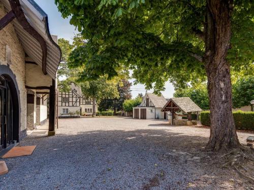 a large tree next to a building with a driveway at Authentic group house in Vielsalm with sauna and bubble bath in Vielsalm