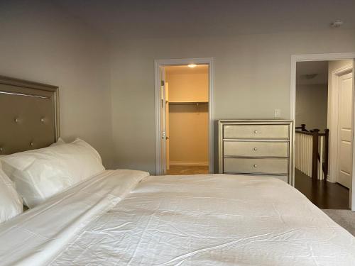 a bedroom with a large white bed and a dresser at Stay with Star in Ottawa