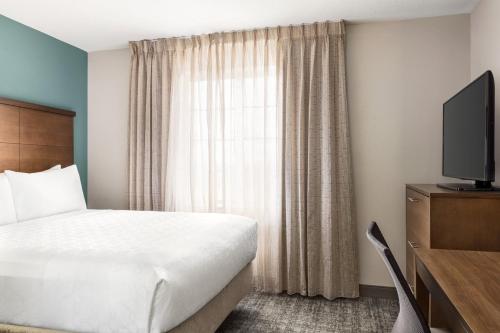 a hotel room with a bed and a television at Staybridge Suites Fort Wayne by IHG in Fort Wayne