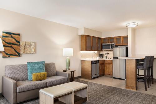 a living room with a couch and a kitchen at Staybridge Suites Fort Wayne by IHG in Fort Wayne