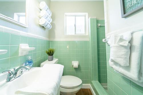 a bathroom with green tiles and a toilet and a sink at Renovated Studio - Steps to Beach, POOL, & Cabana! in Panama City Beach