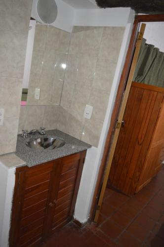 a bathroom with a sink and a wooden door at Cabañas Tres Ríos Vacacional in Villa Cura Brochero