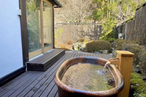 une baignoire sur une terrasse avec un étang dans l'établissement 芹生庵, à Kyoto