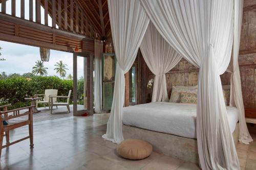 um quarto com uma cama de dossel e um pátio em Bennu House em Ubud