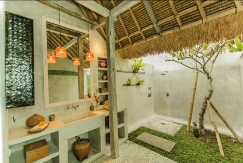 a bathroom with a sink and a tree in it at Bennu House in Ubud