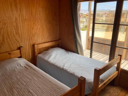a bedroom with two beds and a large window at Portofino Surf Camp in Ciudad de Chañaral