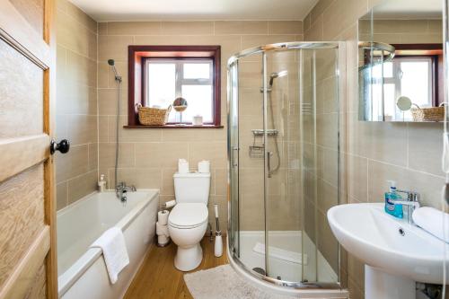 a bathroom with a shower and a toilet and a sink at Elegant 2BD House with Garden and Decked Patio in London