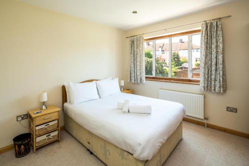 a bedroom with a large bed and a window at Elegant 2BD House with Garden and Decked Patio in London