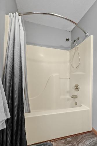 a bathroom with a shower curtain and a tub at LONG LAKE RETREAT- Hot tub, Pool table, Firepit in Traverse City