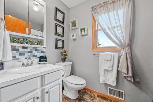 a bathroom with a toilet and a sink and a window at LONG LAKE RETREAT- Hot tub, Pool table, Firepit in Traverse City