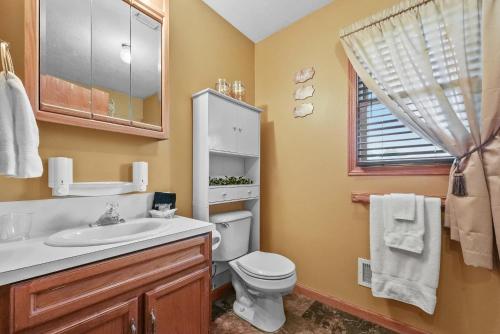 a bathroom with a toilet and a sink and a window at LONG LAKE RETREAT- Hot tub, Pool table, Firepit in Traverse City