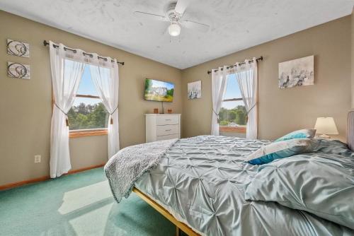 a bedroom with a bed and two windows at LONG LAKE RETREAT- Hot tub, Pool table, Firepit in Traverse City