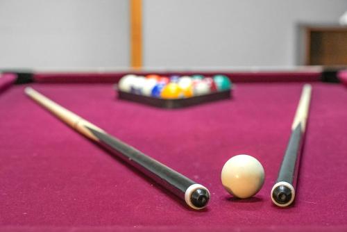 two cue sticks and a cue ball on a pool table at LONG LAKE RETREAT- Hot tub, Pool table, Firepit in Traverse City