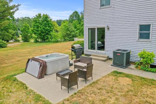 a backyard with a hot tub and chairs and a grill at LONG LAKE RETREAT- Hot tub, Pool table, Firepit in Traverse City